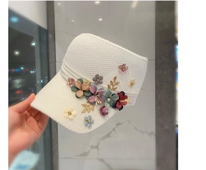 Detailed macro view of white knitted sun visor with 3D floral accents and pearls