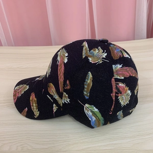 Detail of colorful feather prints on a black cotton baseball cap with curved brim