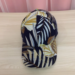 Navy blue baseball cap with tropical leaf print on light wood background