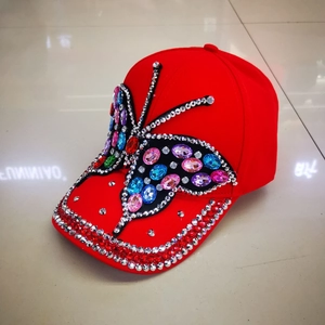 Red baseball cap with colorful rhinestone butterfly design and sparkly studded brim