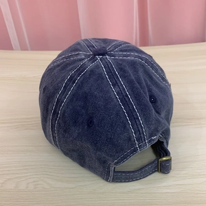 Detail of adjustable metal buckle and contrast stitching on washed cotton baseball cap