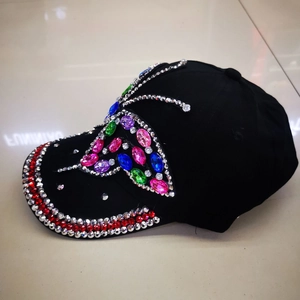 Close-up of colorful rhinestone butterfly design on a black denim baseball cap