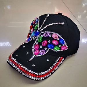 Detailed view of handmade crystal butterfly rhinestones on a black denim baseball cap