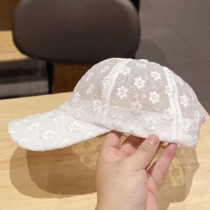 Dettaglio del cappello da baseball in pizzo bianco con ricami floreali e rete traspirante