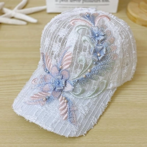 Detailed embroidery with white lace floral textures and pearls on a summer baseball cap