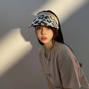 Detail of wide brim cow print straw sun visor hat on model with aesthetic light and shadow