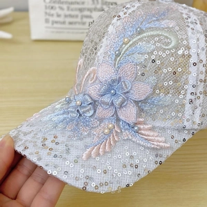 Close-up of white mesh baseball cap featuring silver sequins and lace floral details