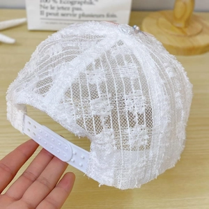 Detail of white lace mesh baseball cap showing breathable texture and adjustable snapback