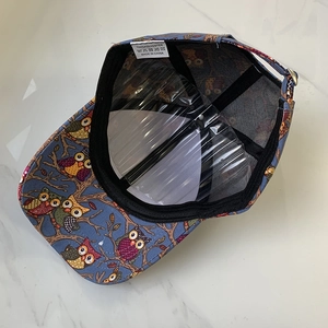 Detail of navy blue baseball cap interior showing 100% polyester label and owl print