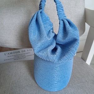 Chic royal blue pleated bucket handbag with ruffled handle shown in a lifestyle setting