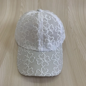 Detailed close-up of white mesh baseball cap featuring elegant four-leaf clover embroidery