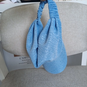 Detail of light blue pleated fabric tote bag with flexible ruched handle design