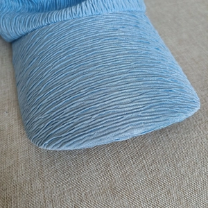 Detail of light blue sun hat brim featuring textured seersucker fabric on beige burlap