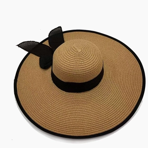 Detailed close-up of woven straw sun hat texture with black ribbon and bow detail