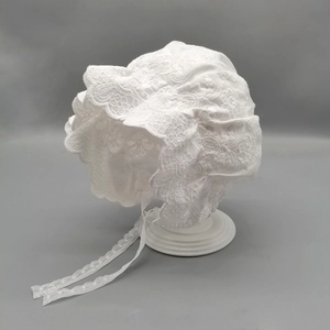 White lace baby sun hat with vintage embroidery and silk ties on a display stand