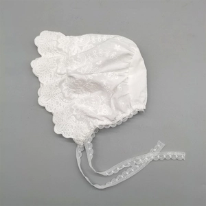 Detailed view of white baby lace bonnet with floral embroidery and delicate ruffles