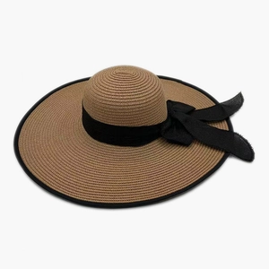 Detailed top view of a wide brim straw sun hat with black ribbon bow and textured weaving