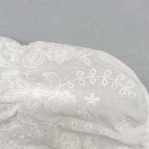 Elegant white cotton baby sun hat featuring intricate floral lace and embroidered eyelets