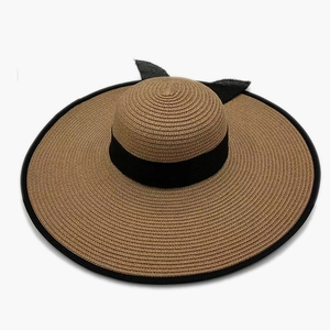 Women's brown straw sun hat with wide brim and black ribbon bow for beach vacations