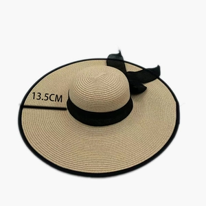 Detail view of the 13.5cm wide brim of a woven straw hat with black bow and edge