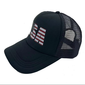 Detail of black trucker hat featuring USA letters with American flag print and mesh back