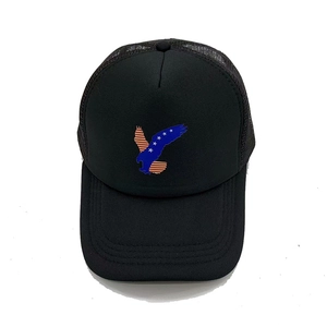 Detail of black trucker hat featuring an American flag eagle patch and mesh back