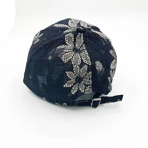 Dettaglio di pizzo nero con motivi floreali e fibbia in metallo regolabile sul cappello