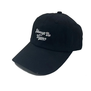 Close-up of Always Be Better cursive embroidery on a premium black cotton baseball cap