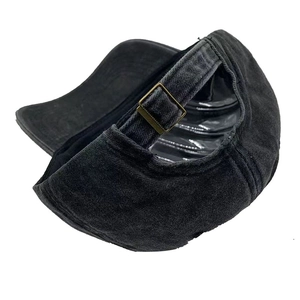 Detail of dark grey washed denim baseball cap featuring adjustable bronze metal buckle