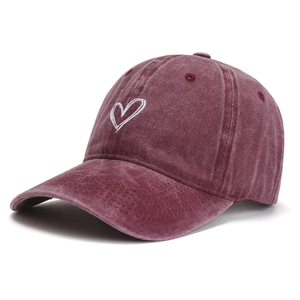 Detailed close-up of burgundy washed cotton baseball cap with white heart embroidery
