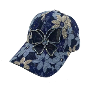 Vue détaillée du motif en dentelle et du papillon en strass sur la casquette de baseball