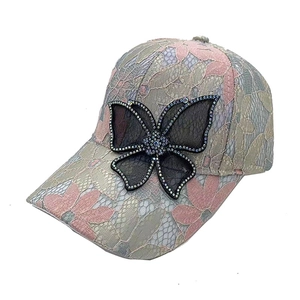 Vue détaillée de la dentelle florale et du papillon en strass sur la casquette