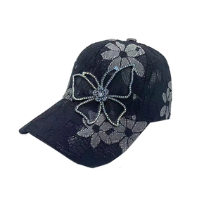 Gros plan détaillé sur la dentelle florale grise et le papillon en strass de la casquette