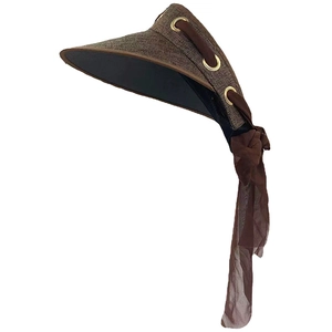 Detail of a brown wide-brim sun hat with gold eyelets and a flowing chiffon ribbon