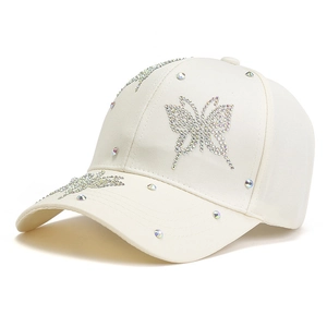 Cream-colored baseball cap with sparkling rhinestone butterfly design and curved brim