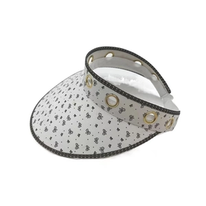 Detailed top view of white shell sun hat with black butterfly pattern and gold eyelets
