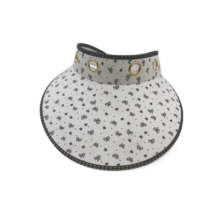 Close-up of white sun hat with black butterfly print and metallic eyelet details