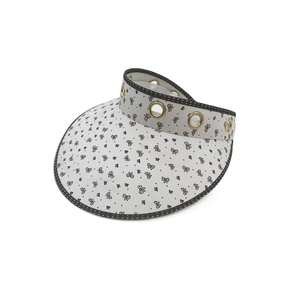 Macro detail of sun visor hat featuring golden eyelets and black polka dot brim edge
