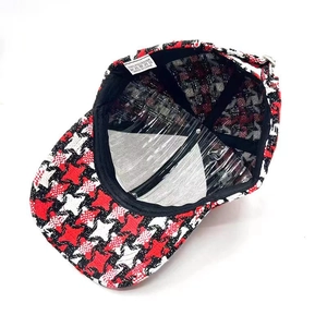 Detail view of red and black houndstooth baseball cap with 100% polyester wash label