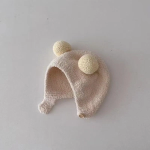 Detail of baby plush earflap hat with soft lamb wool texture and wooden button closure