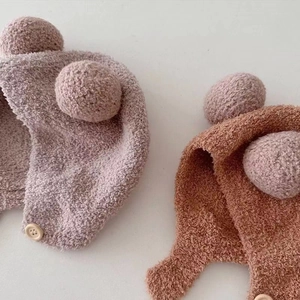 Detailed texture of baby winter plush earflap hats with fluffy pom-poms and buttons
