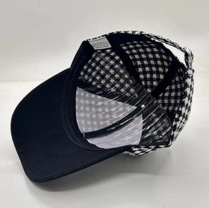 Detail of checkered baseball cap interior showing 100% polyester label and metal buckle