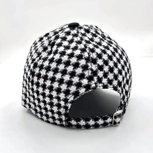 Detail view of the houndstooth pattern fabric and adjustable metal buckle on back of the cap