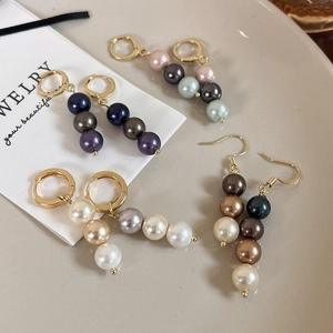 Détail des boucles d'oreilles pendantes en perles dégradées multicolores sur plateau en céramique