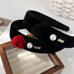 Elegant black velvet headbands with red roses and pearls displayed on a wooden box