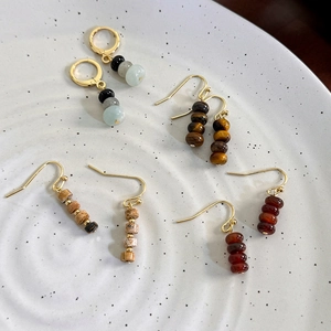 Vintage gold earrings with natural tiger eye and agate beads on a white ceramic tray