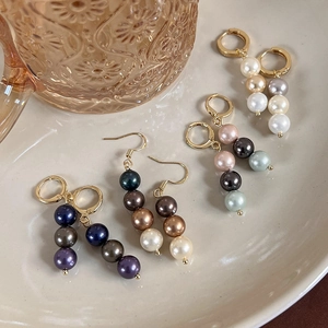 Élégantes boucles d'oreilles vintage en or avec perles colorées dans un plat en céramique