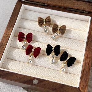 Detailed shot of three pairs of velvet bow earrings with water drop pendants in a wooden box