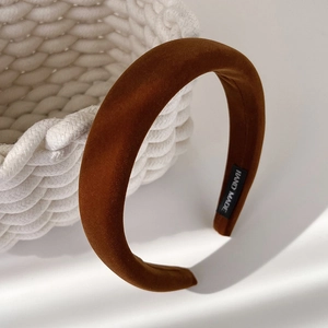 Detail view of handmade brown velvet padded headband with handmade label on knit background
