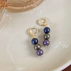 Détail de boucles d'oreilles vintage avec perles dégradées violettes sur plateau en céramique